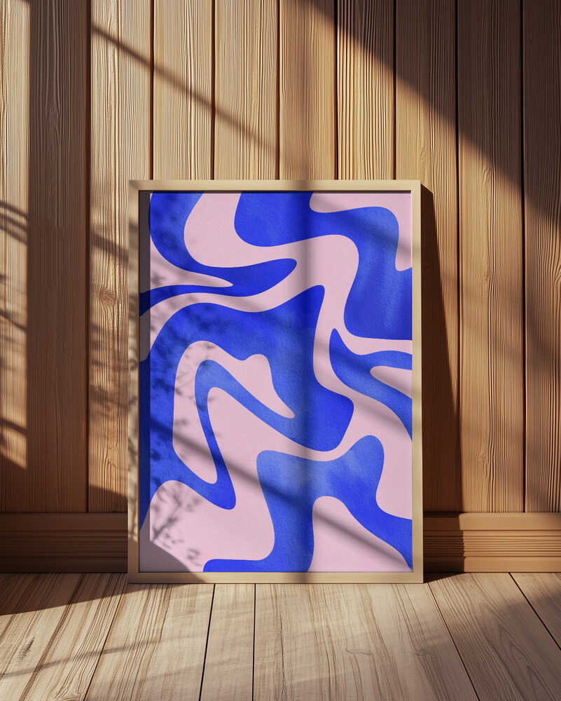 Abstract art print featuring bold wavy shapes in deep blue and soft pink tones. Displayed in a light wooden frame leaning against a wooden wall, with natural sunlight and shadows. Modern geometric wall art that adds a vibrant, artistic touch to Scandinavian interiors.