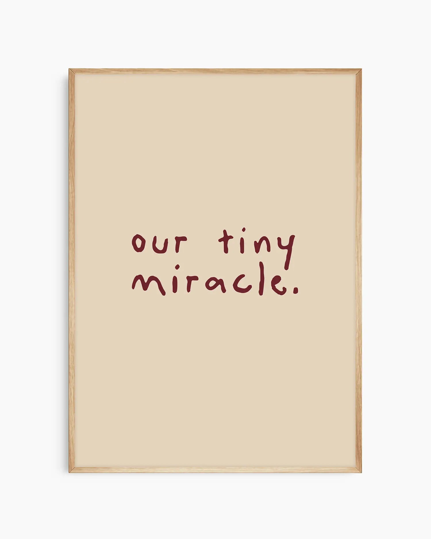 Beige nursery poster with 'our tiny miracle.' text in brown framed in an oak frame.