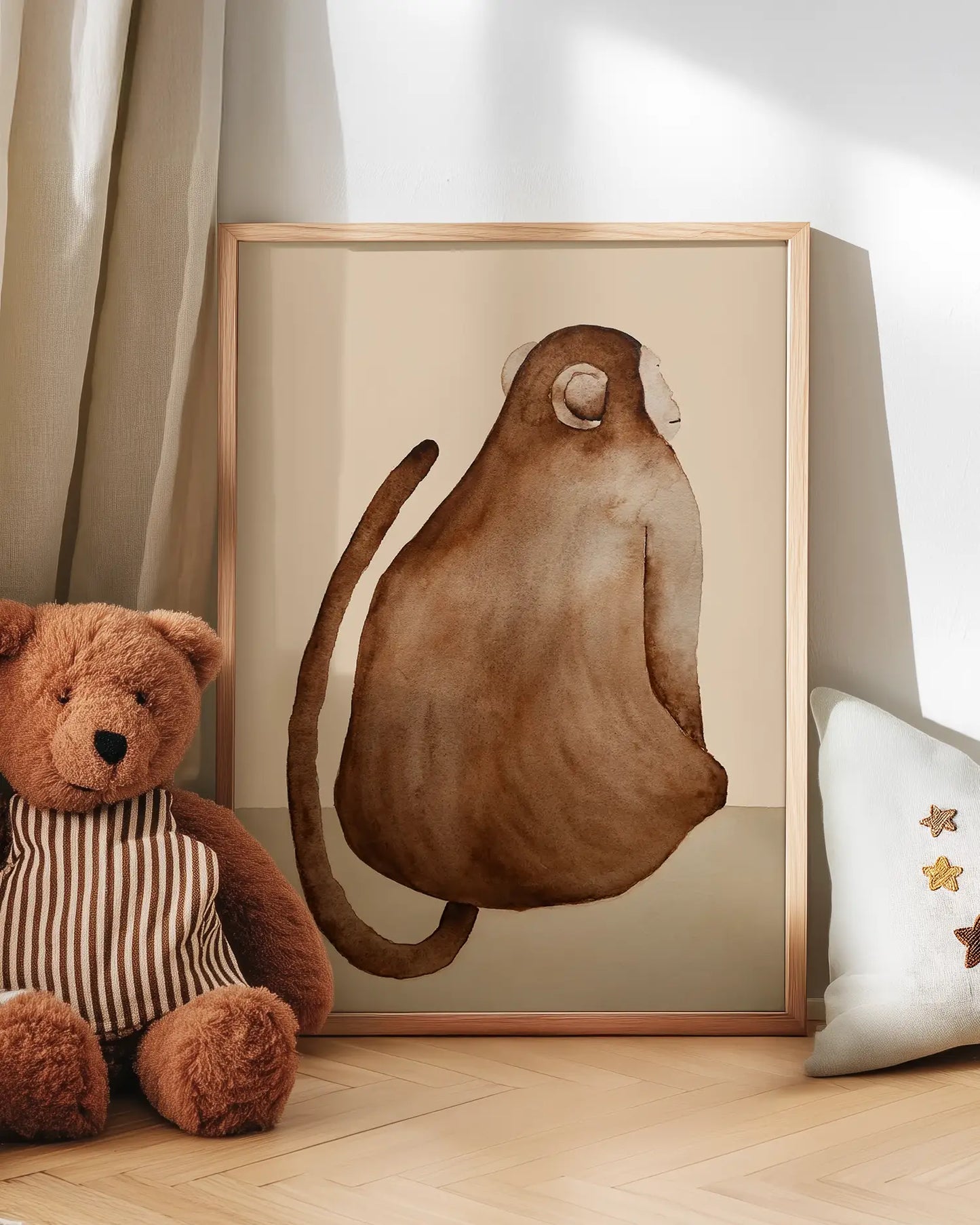 Framed artwork of a monkey on a wall next to a teddy bear and decorative pillow.