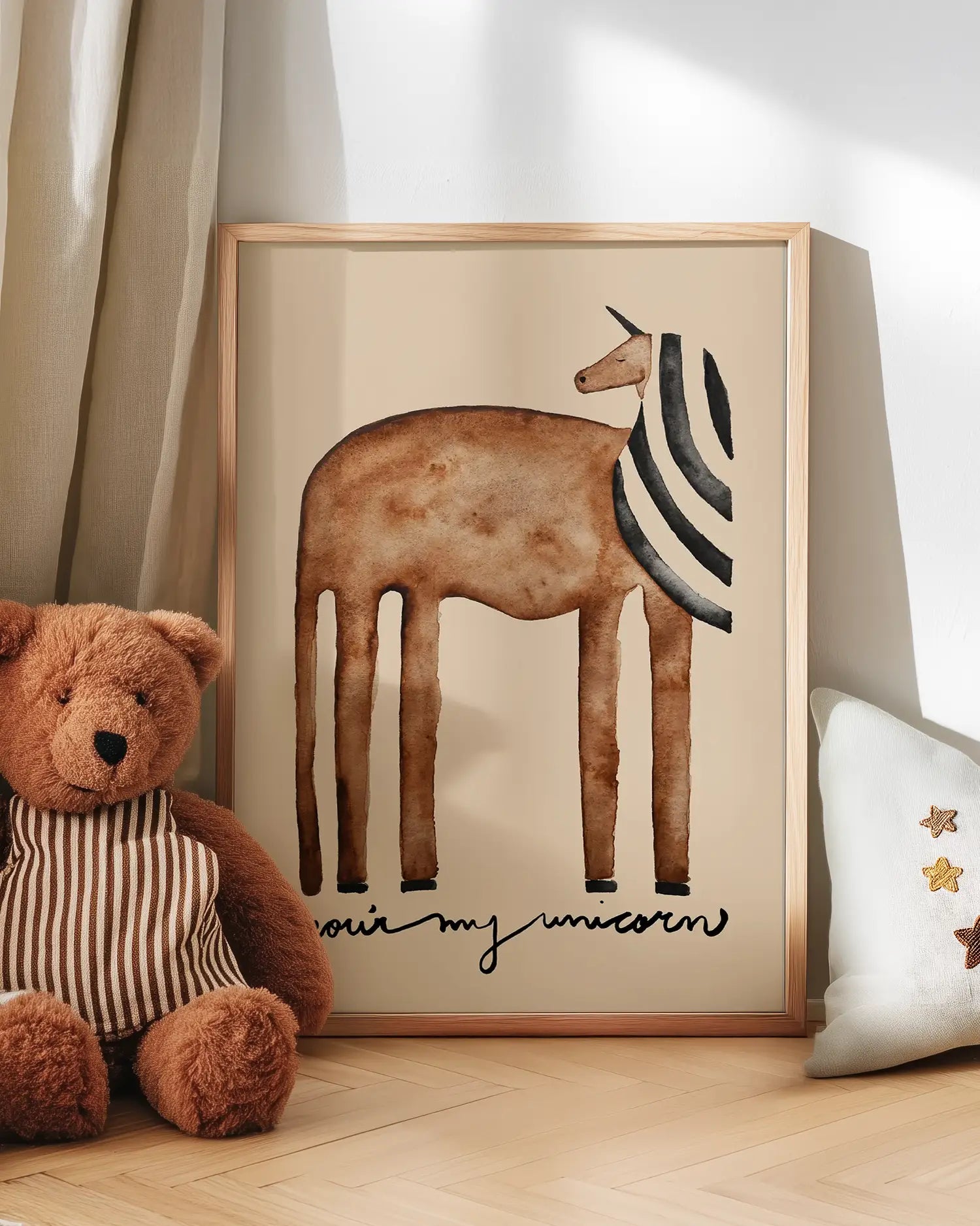 Framed illustration of a unicorn with 'our my unicorn' text next to a teddy bear on a wooden floor.