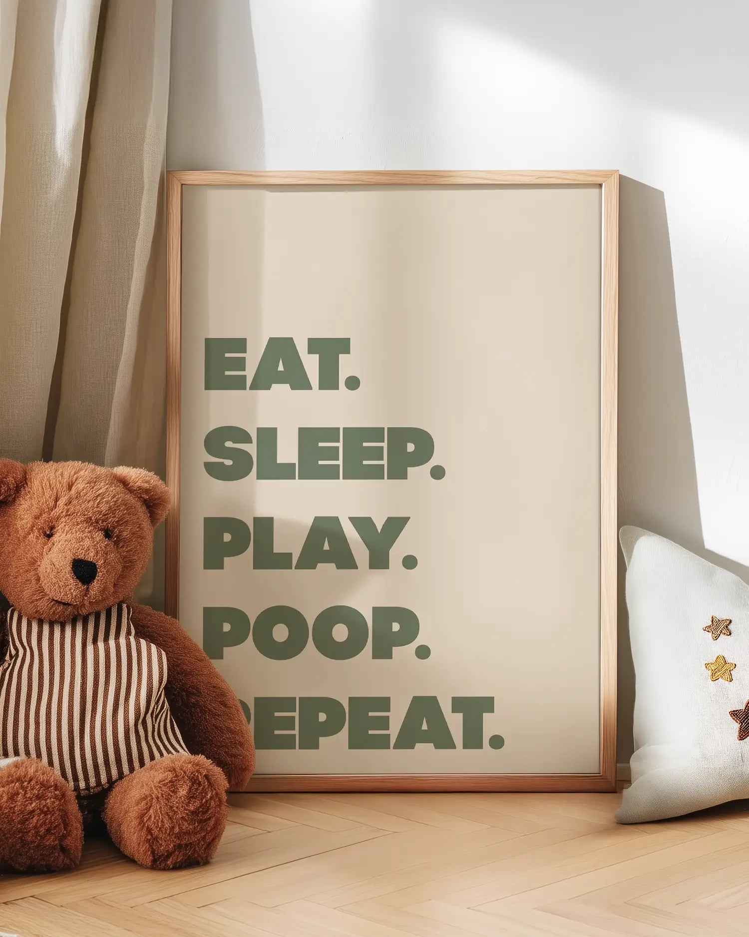 Poster with 'EAT. SLEEP. PLAY. POOP. REPEAT.' text next to a teddy bear on a wooden floor.