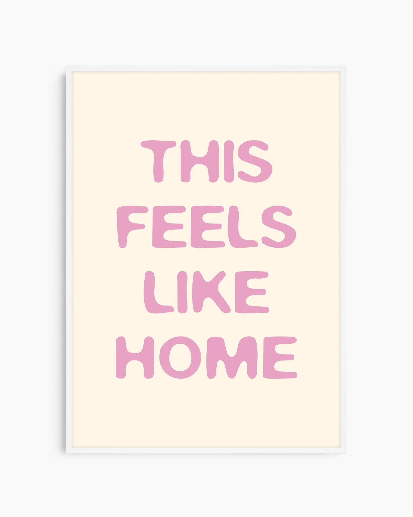 Nursery poster with the text 'This feels like home' written in pink on a beige background, framed in a white wooden frame