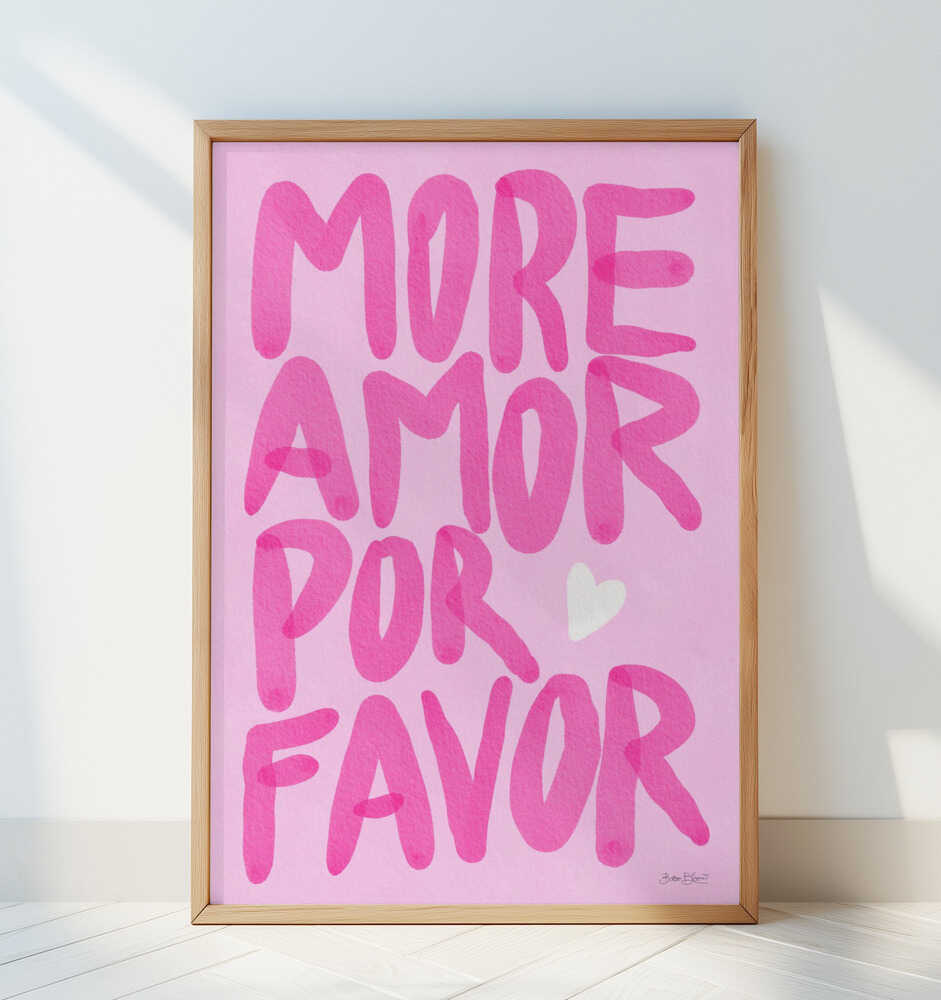Framed nursery poster with pink text 'MORE AMOR POR FAVOR' leaning against a white wall.